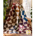 A colorful quilt draped over a chair, featuring a star pattern in various shades against a light background.