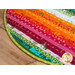 Colorful circular fabric rug with bold patterns, featuring vibrant hues of orange, pink, and green.