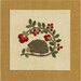 Embroidery of a hedgehog surrounded by flowers and leaves on a textured background.