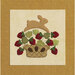 An applique design featuring a brown bunny jumping above a basket overflowing with strawberries.