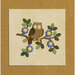 Owl sitting on a branch with green leaves and blue flowers against a beige background.