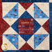 Stars and stripes quilt made of geometric blocks featuring red, blue, and cream, patriotic fabric prints.