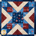 Stars and stripes quilt made of geometric blocks featuring red, blue, and cream, patriotic fabric prints.