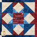 Stars and stripes quilt made of geometric blocks featuring red, blue, and cream, patriotic fabric prints.