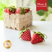 An image of small strawberry pincushions on a table and in a cotton basket.