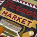 Close-up of a textile design featuring the words Farmer Market in bold letters, surrounded by decorative elements including a basket and vegetables, with a variety of textures and colors.