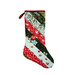 Christmas stocking made of various holiday themed fabrics hanging on a white wall.