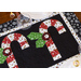 Black and white table runner featuring 3 candy canes with fabric yo-yos, all made of Winter themed fabric prints.