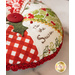 Red, green, and white, pincushion made of Christmas themed fabrics, accented with red button and holly leaf appliqué