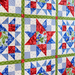 Colorful patchwork quilt featuring star patterns in red, blue, and green floral and checkered designs.