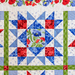 Colorful quilt with star pattern, featuring blue, red, green, and floral fabric in a geometric design.