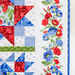 A patchwork quilt featuring red, blue, and green patterns with floral designs and geometric shapes.