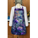 Colorful floral and dragonfly themed apron displayed on a mannequin, paired with a white long-sleeve shirt.