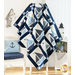 Quilt featuring blocks of geometric sail boats made of white and blue fabrics draped over furniture.