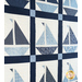 Quilt featuring blocks of geometric sail boats made of white and blue fabrics.