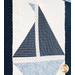 Quilt block of geometric sail boat made of white and blue floral and striped fabrics.