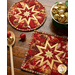 Round hot pad with central folded star design made of red and cream Christmas themed fabrics.