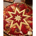 Square hot pad with central folded star design made of red and cream Christmas themed fabrics.