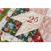 Close up of table runner detail showing a corner of a quilted star with fabric featuring numbers and Christmas floral motifs