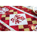 Christmas themed table runner featuring bell designs made of red and cream snowflake fabrics.