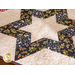 Table runner with 3 hollow star design made of red, black, and green winter theme printed fabric on cream.