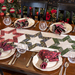 A festive dining table set with elegant plates, glasses, and star-patterned table runner, surrounded by holiday decor.