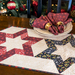 A festive table setting featuring a star-patterned quilted runner, decorative napkins, and a plate.