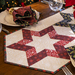 A hexagonal quilted table centerpiece features red and patterned stars on a light background.