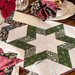 Colorful quilted table runner featuring a star design, surrounded by festive napkins and dinnerware.