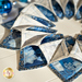 A circular arrangement of fabric pieces in shades of blue and white, resembling a decorative quilt pattern, sits on a light wooden surface.