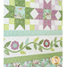 Quilt filled with sawtooth stars and flower appliqué in pastel green and purple colors.