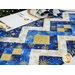 angled shot of the blue and gold diamond patterned table runner atop a white table with place settings behind