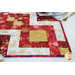 Table runner with strips of fabric in a lattice design made from metallic red and cream Christmas and snowflake printed fabrics.