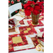 Table runner with strips of fabric in a lattice design made from metallic red and cream Christmas and snowflake printed fabrics.