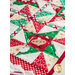 Table runner with triangle pinwheel design in Christmas themed Santa fabrics in red, white, and green.