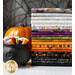 A stack of Halloween-themed fabric bolts in orange, black, purple, and gray colors is displayed beside a small black cauldron filled with colorful spools of thread. An orange pumpkin is placed in the background, against a web-like backdrop.