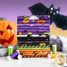 A stack of Halloween-themed fabric in various colors, including purple, black, orange, and white, with patterns like pumpkins, ghosts, and bats. In the background, there is a carved pumpkin and a bat decoration, along with spools of green and white thread.