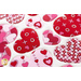 Close up angled shot of heart table topper with different sized hearts in red and pink on a white background on a white table