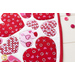 Close up angled shot of heart table topper with different sized hearts in red and pink on a white background on a white table with red and pink buttons scattered all over the table