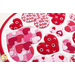 Close up angled shot of heart table topper with different sized hearts in red and pink on a white background on a white table