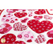 Close up angled shot of heart table topper with different sized hearts in red and pink on a white background on a white table with red and pink buttons scattered all over the table