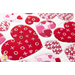Close up angled shot of heart table topper with different sized hearts in red and pink on a white background on a white table