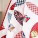 Close up of a red quite and blue quilt draped over furniture showing fabric detail with a white wall in the background