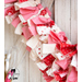 Close up of one side of fabric wreath showing detail of red, pink, and white fabrics on a white wooden wall