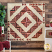 Finished Log Cabin Bouquet quilt pinned to a brown paneled wall with a chair, a shelf, and a green plant in the background