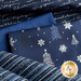 Close up of navy blue fabric with metallic silver winter motifs layered atop one another