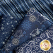 Close up of navy blue fabric with metallic silver winter motifs layered atop one another