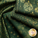 A stack of green fabrics featuring various gold patterns, including snowflakes, ornaments, and swirls.