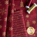 A flat lay of red fabric featuring gold snowflake patterns and handwritten text, accompanied by spools of burgundy and gold thread.