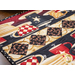 Close up of one end of the table runner showing detail stitching of the center checkered stripe made up of alternating diamonds made with coffee bean fabric, and triangles made of cream fabric with coffee rings all over it